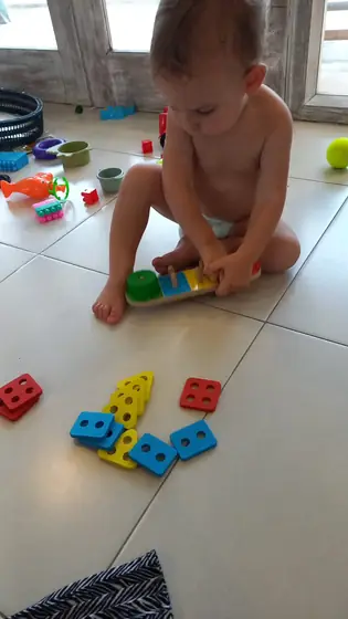 A toddler stacking colourful toy blocks