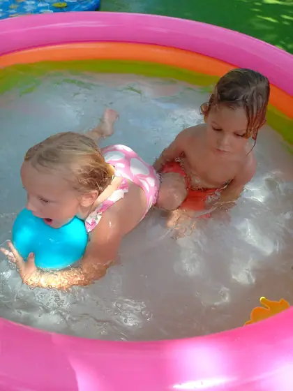 Two little ones splashing in a paddling pool