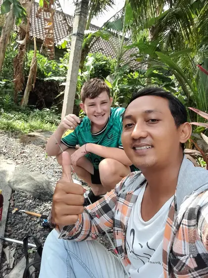 A smiling boy and a team member taking a selfie outdoors