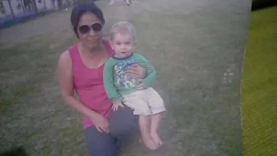 A nanny sitting with a toddler on the grass