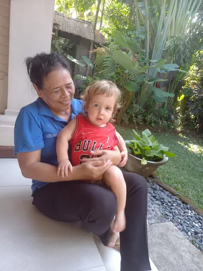 A nanny holding a baby on her lap in a garden