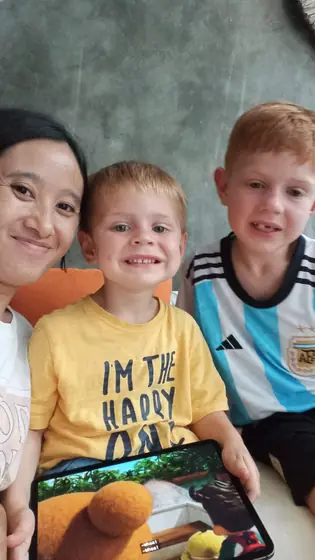 A nanny taking a selfie with two smiling boys