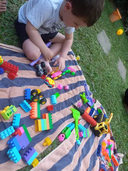 A boy building with toy blocks on a picnic blanket